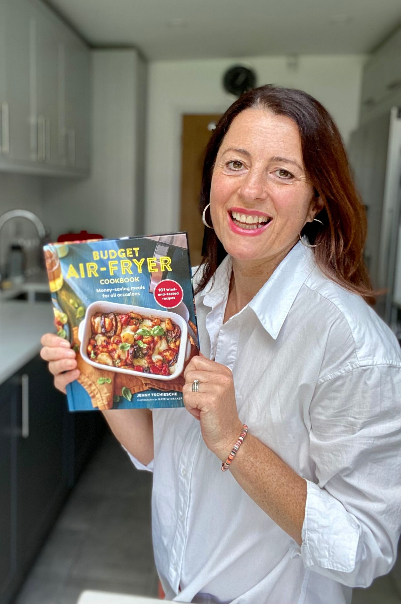 Jenny Tschiesche holding her book entitled Budget Air Fryer Cookbook